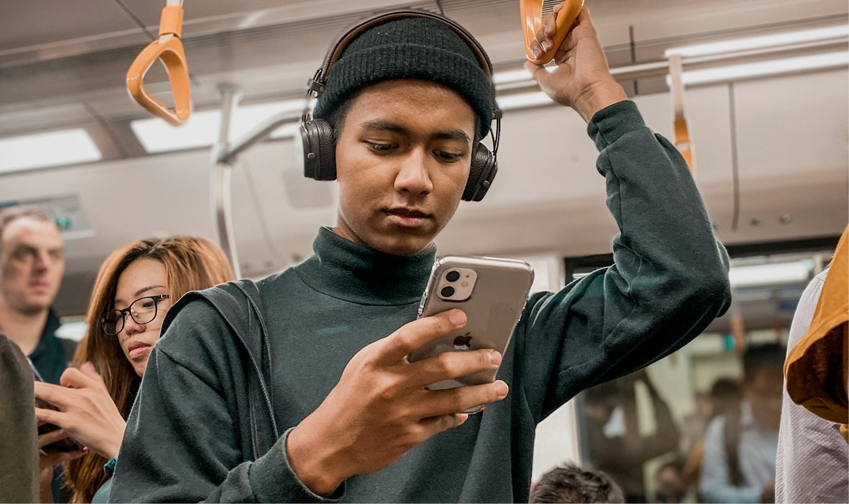 En person står på en tunnelbana och tittar ner i sin telefon.